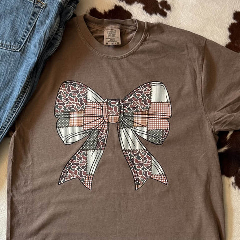 Brown t-shirt with a large camo bow design on a cowhide rug