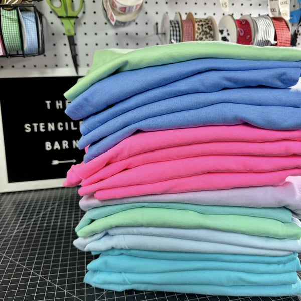 Stack of colorful folded fabrics on a cutting mat with craft supplies in the background.