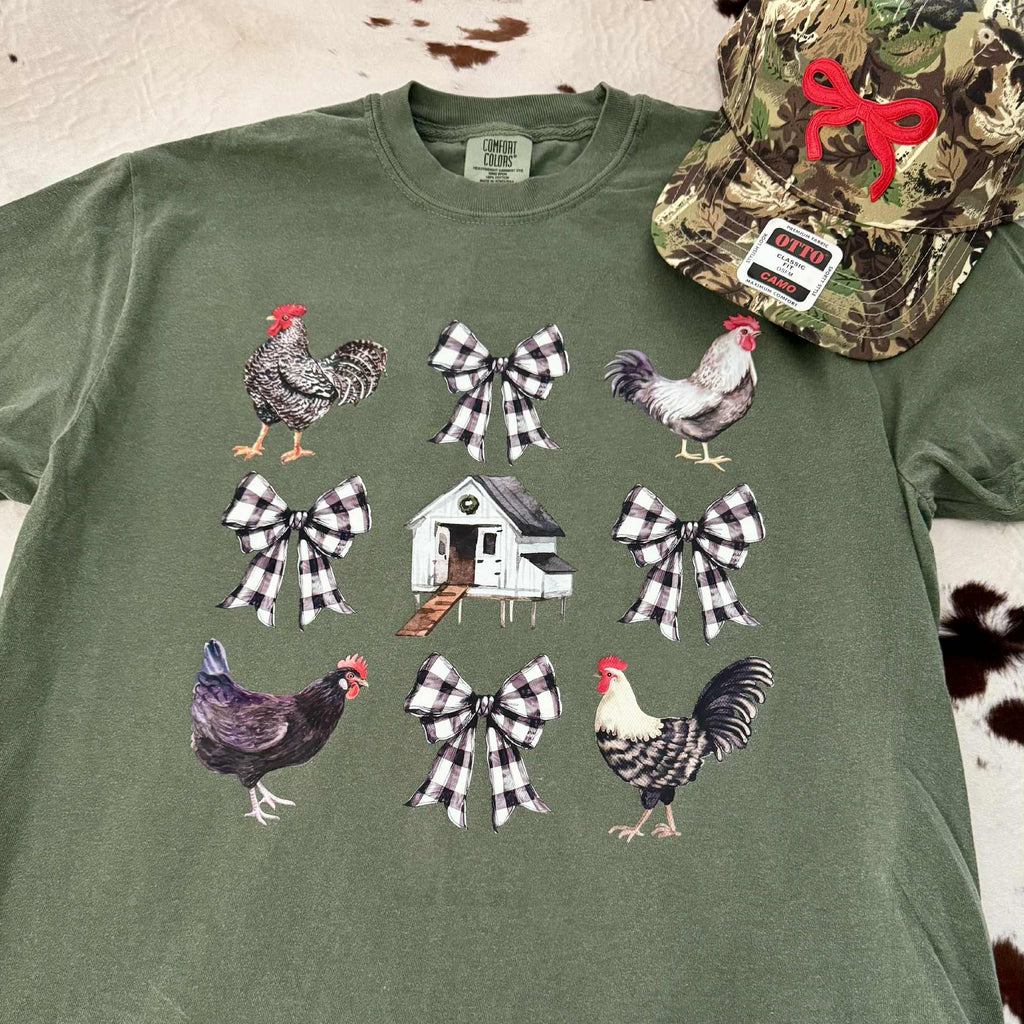 Green t-shirt with rooster and bow design, worn with camouflage hat.