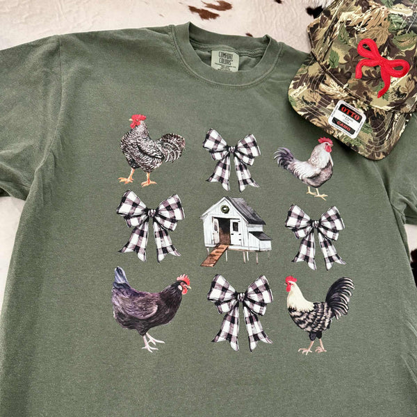 Green t-shirt with rooster, bow, and chicken coop design on a neutral background