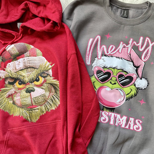 Red hoodie with mean green man design and gray hoodie with 'Merry Christmas' design.