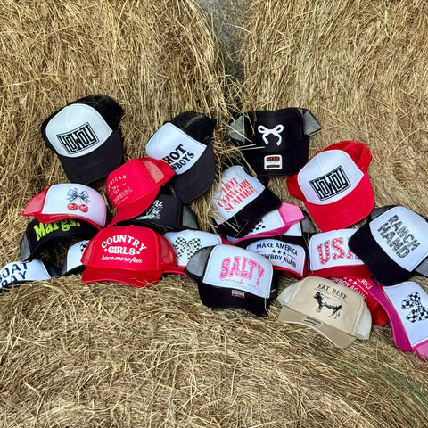 Collection of various hats on a hay bale