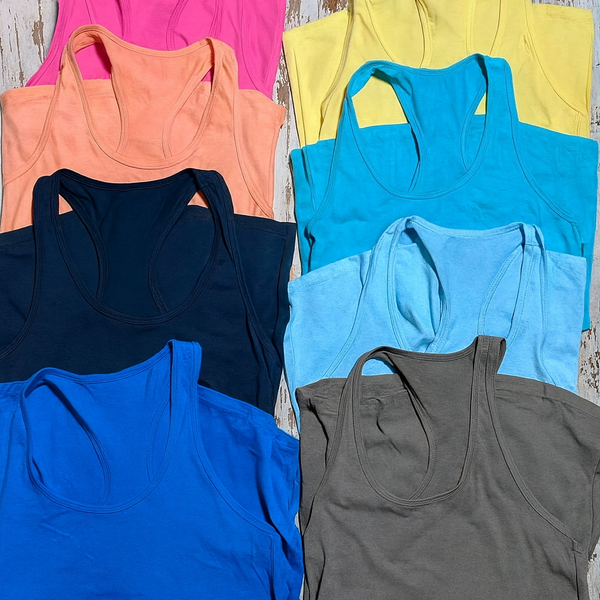 Collection of colorful tank tops arranged on a wooden surface.