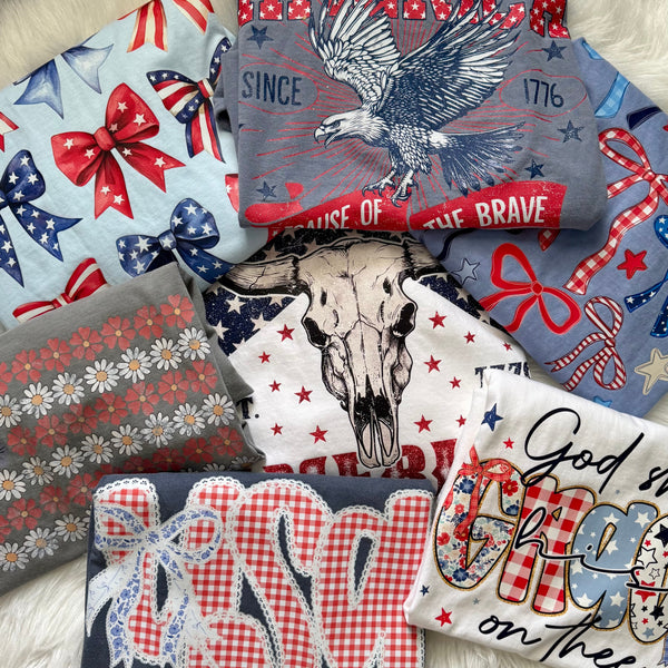 Collection of graphic tees with patriotic designs including stars, stripes, and an eagle.