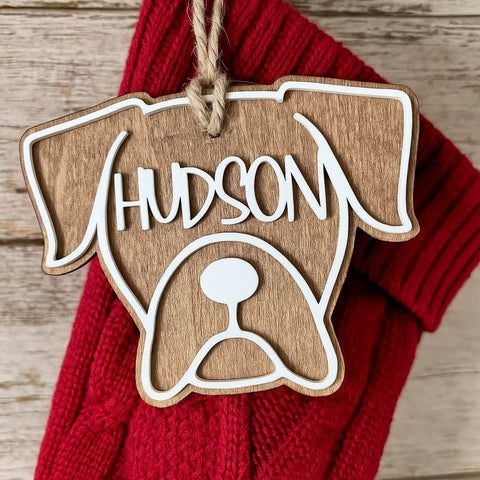 Wooden ornament shaped like a Boxer dog with personalized name engraved, hanging on a red Christmas stocking.