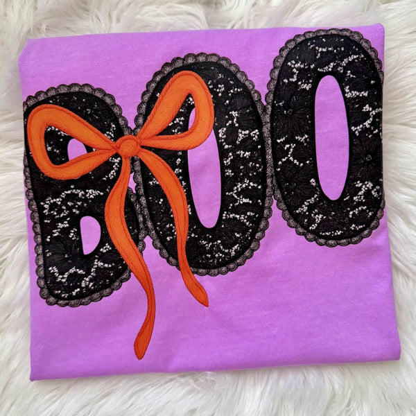 Purple Halloween t-shirt with 'BOO' and a bow design on a fluffy white background