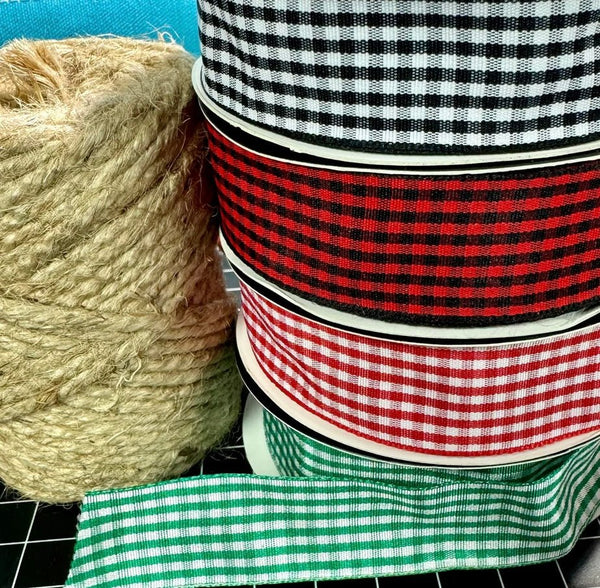 Stack of ribbons with a spool of twine on a tiled surface