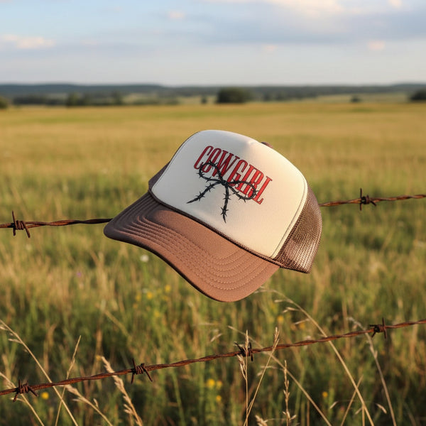 Cowgirl trucker hat with red COWGIRL text and barbed wire bow on brown and cream foam cap.