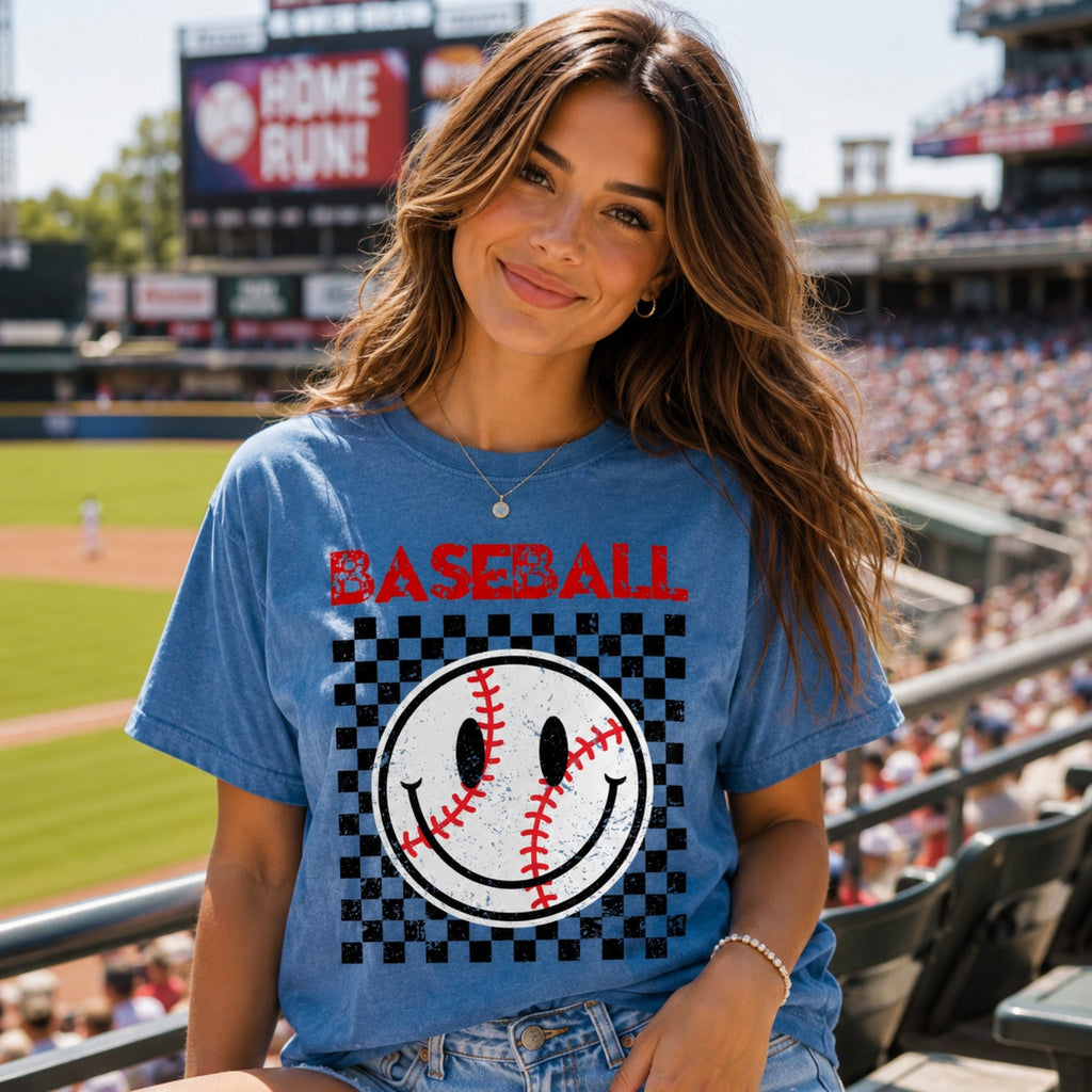 Young woman wearing Comfort Colors Blue Jean baseball graphic tee sitting in a baseball stadium during game day