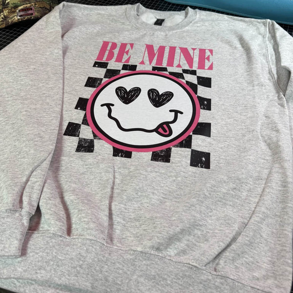 Gray sweatshirt with a smiley face and 'Be Mine' text on a checkered background