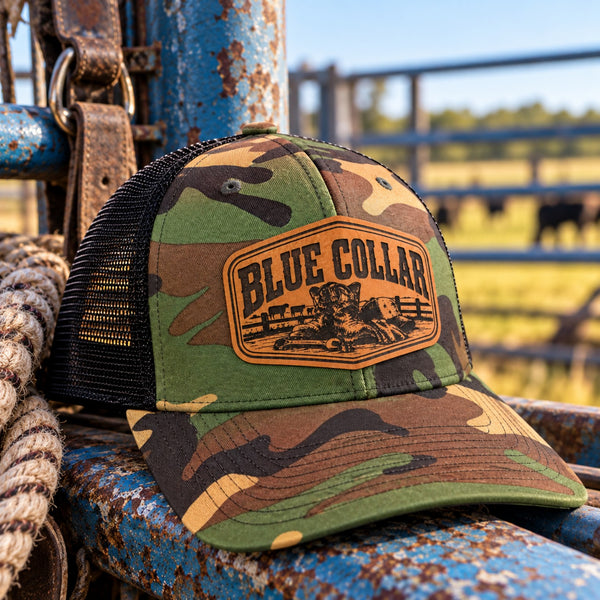 Camo Blue Collar leather patch hat with black mesh back in a cattle ranch setting
