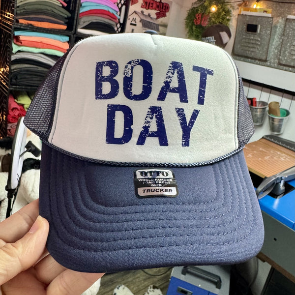 Navy and white foam trucker hat featuring a distressed Boat Day graphic for boating, lake days, and coastal adventures.