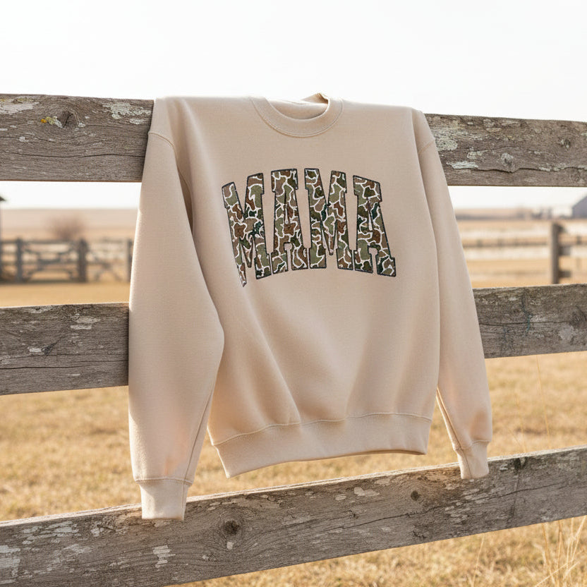 Beige sweatshirt with 'MAMA' in camouflage print on a light gray background