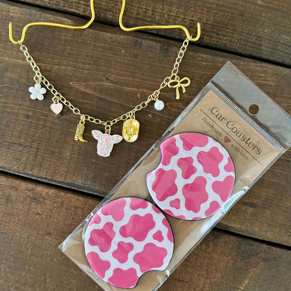 Pink cow print car charm necklace with matching pink cow print car coasters.