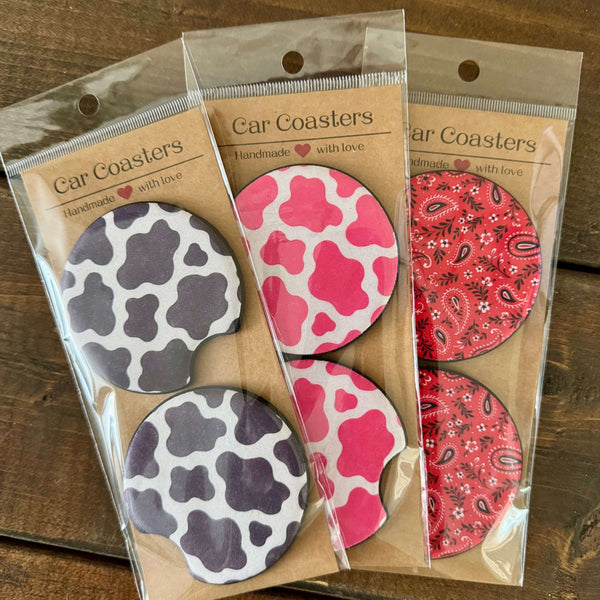 Set of car coasters in black cow, pink cow, and red paisley prints.