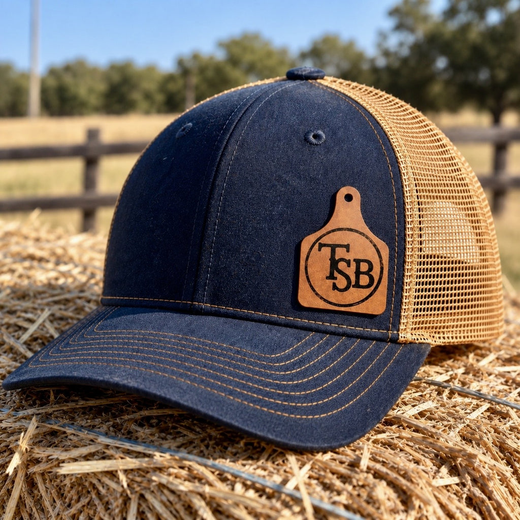 Custom cattle brand patch hat on navy and tan trucker hat with personalized leatherette ear tag patch