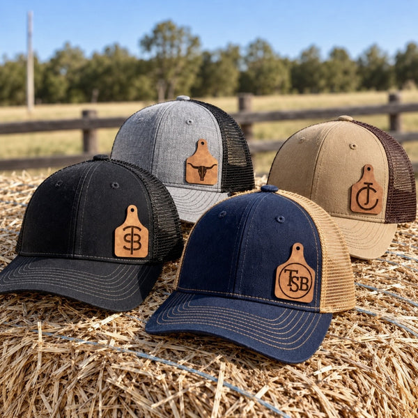 Personalized cattle brand trucker hats in black, gray, tan and navy with custom ear tag patches