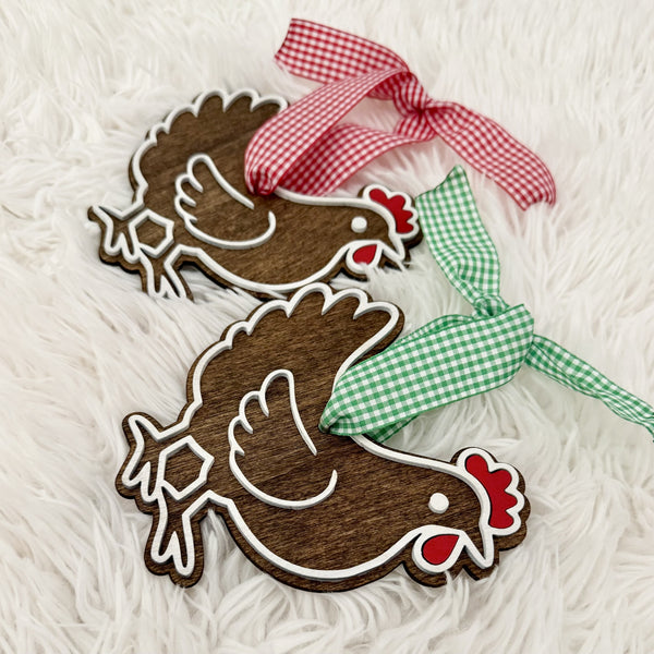 Side view of layered wooden chicken Christmas ornaments showing dimensional white details and gingham ribbon hangers.