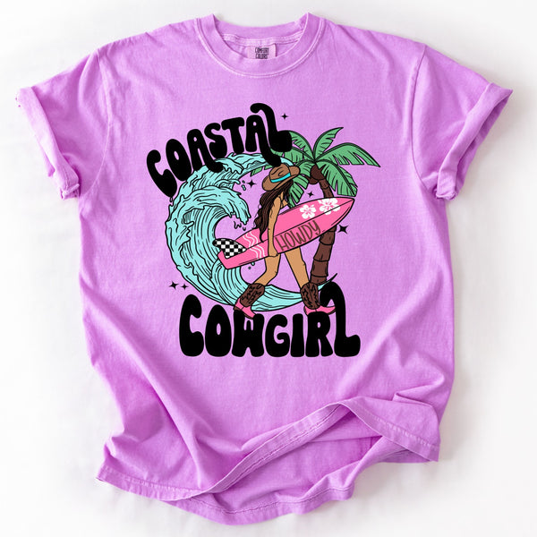 Neon violet comfort colors brand t-shirt with a graphic of a cowgirl on a surfboard and text 'Coastal Cowgirl' on a white background