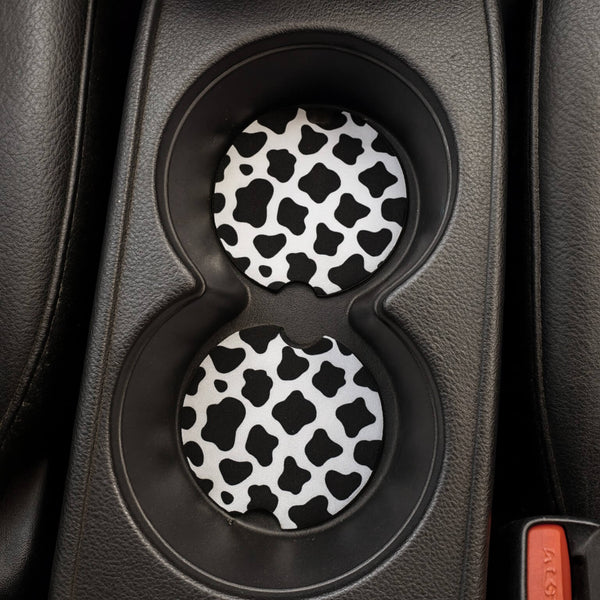 Cow print coasters in a car cup holder