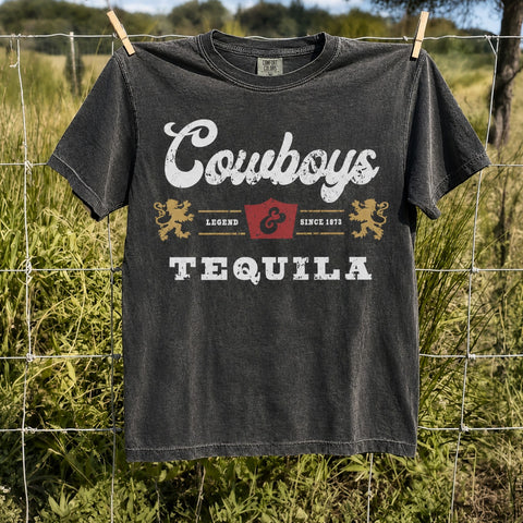 Pepper Comfort Colors Cowboys & Tequila graphic tee hanging on a rustic ranch fence with a vintage western country design.