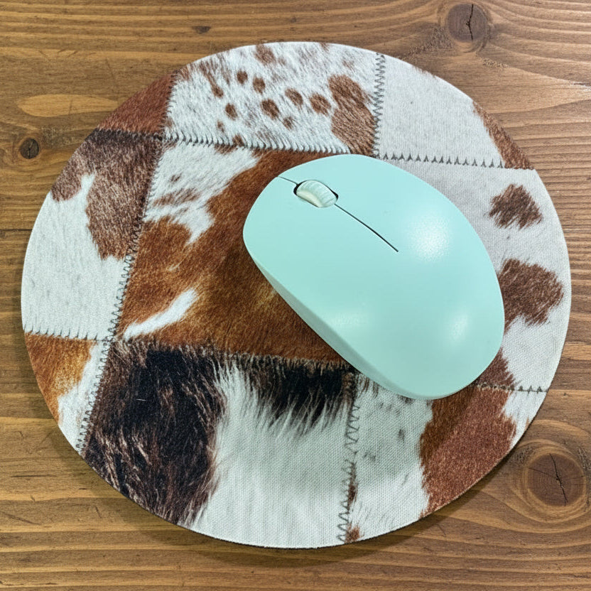 Turquoise mouse on a cow print mouse pad on a wooden surface