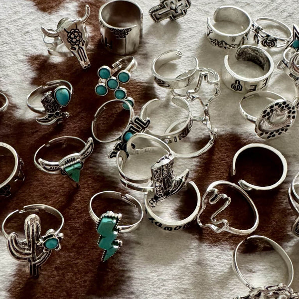 Collection of various turquoise & silver rings with different designs on a textured surface