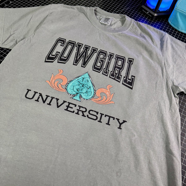 Gray t-shirt with 'Cowgirl University' text and graphic on a grid background