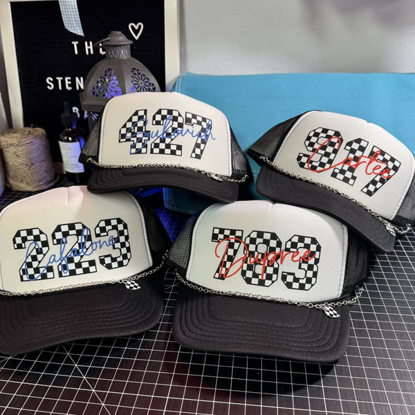 Custom checkered number trucker hats with personalized names, black and white mesh caps, trendy race day style hats with silver hat chains, southern country boutique accessories by The Stenciled Barn