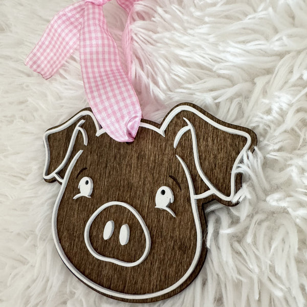 Cute wooden pig face Christmas ornament with white layered details and pink gingham ribbon
