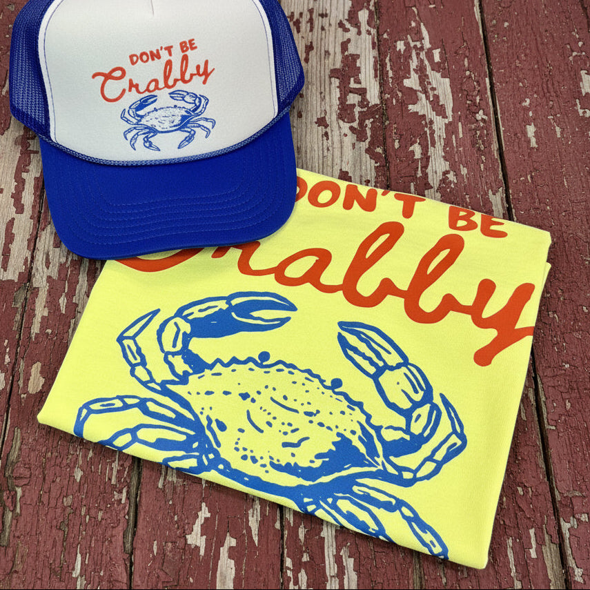 Neon yellow Comfort Colors Don’t Be Crabby graphic tee with matching blue and white trucker hat on rustic barn wood background