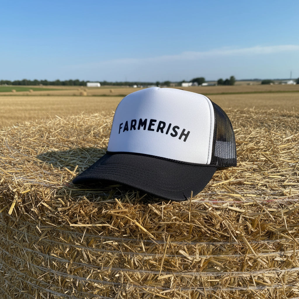 Trucker hat with 'FARMERISH' arched text sitting on a haystack.