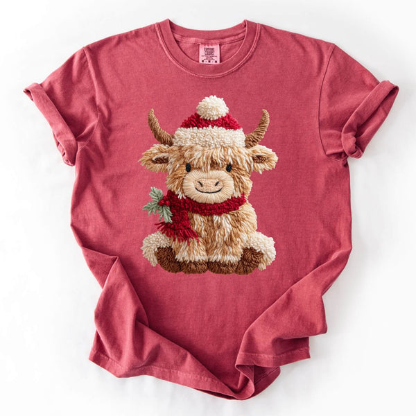 Red t-shirt with a fluffy Highland cow wearing a Santa hat and scarf on a white background