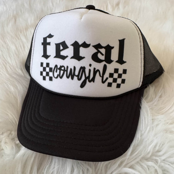 Black and white cap with 'feral cowgirl' text on a fluffy white background