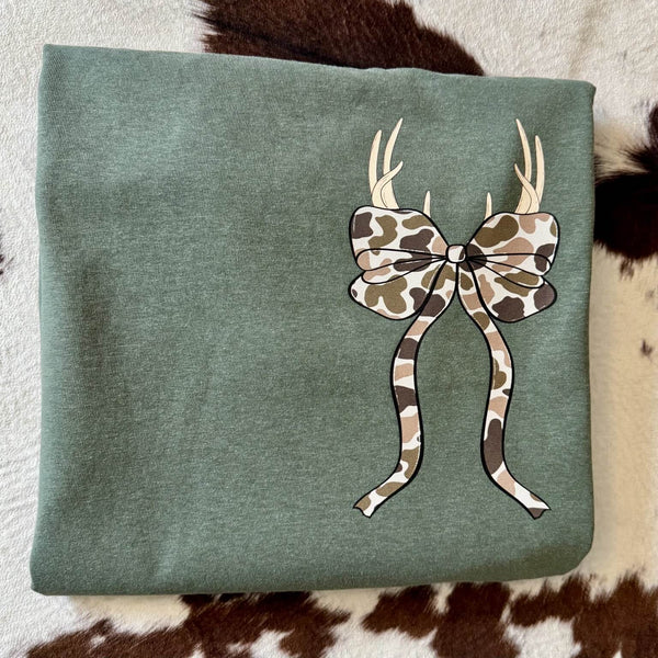 Green fabric with a camouflage bow and antlers design on a patterned background