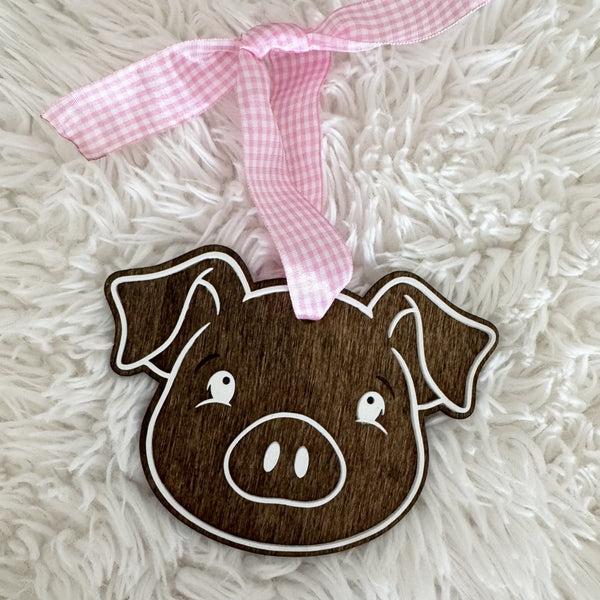 Handmade farmhouse pig Christmas ornament with dark wood finish and pink gingham hanging ribbon