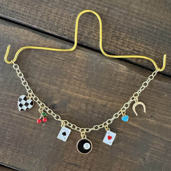 Gold charm chain with western retro charms displayed on rustic wooden background