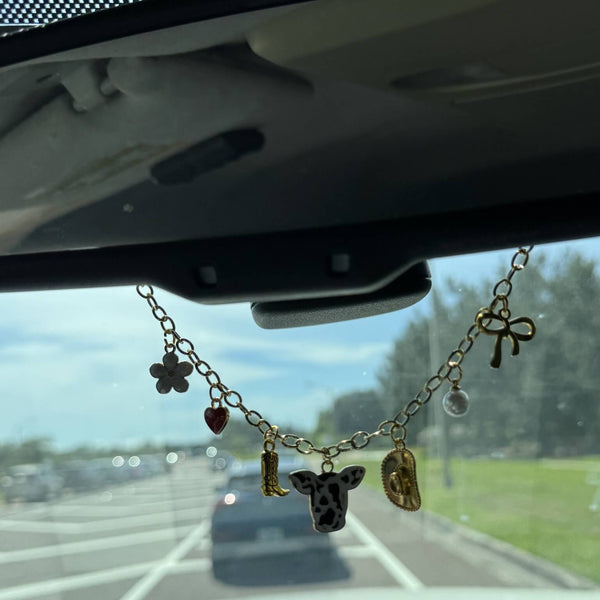 Western cowgirl rearview mirror necklace with charms hanging in car