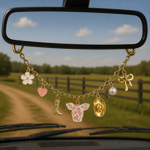 Pink Cow Print Rearview Mirror Charm Necklace with Gold Chain, Boot, Hat, Bow, Pearl & Flower Charms Hanging in a Rustic Country Vehicle