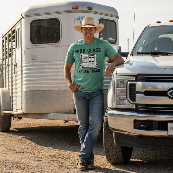 Man wearing green t-shirt with 'High Class Trailer Trash' graphic design standing next to a truck and horse trailer