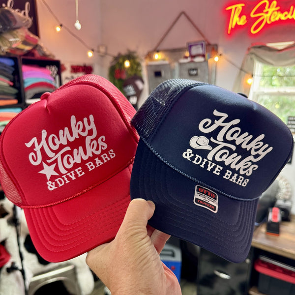 Honky Tonks and Dive Bars foam trucker hats in red and navy blue for country music and western lifestyle fans.