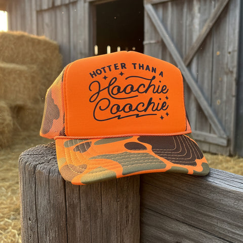 Neon orange camo trucker hat with Hotter Than A Hoochie Coochie graphic in black western script lettering