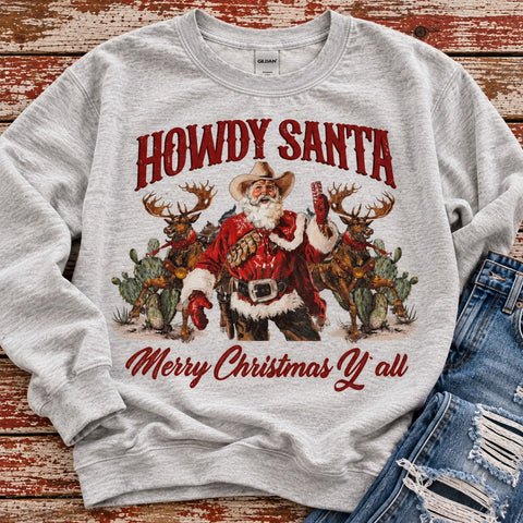 Howdy Santa western Christmas graphic sweatshirt in light gray featuring cowboy Santa, reindeer, red lettering, and Merry Christmas Y’all design on rustic wood background.