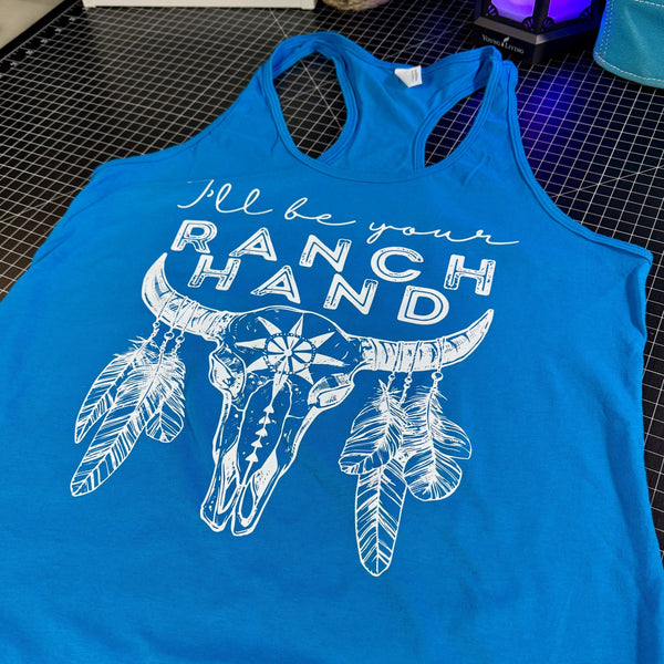 Blue tank top with white graphic and text 'I'll be your ranch hand' on a checkered surface.