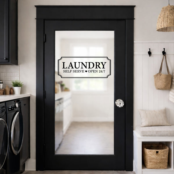 Black door with 'Laundry Self Serve Open 24/7' sign in a laundry room.