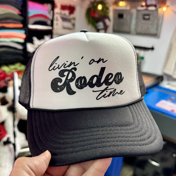 Livin' On Rodeo Time foam trucker hat with western rodeo graphic on black and white trucker cap.