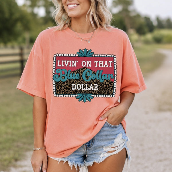 Woman wearing Neon Cantaloupe Comfort Colors Blue Collar Dollar graphic tee with distressed denim shorts