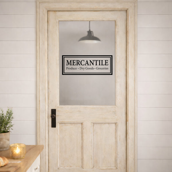 Wooden door with a Mercantile door decal sign in a rustic setting.