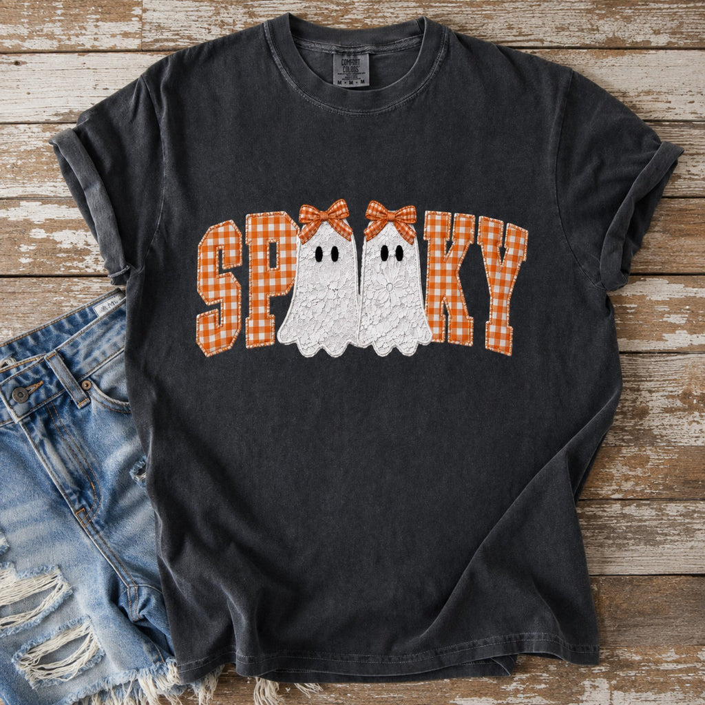 Charcoal Spooky Halloween graphic tee with orange gingham letters and white ghosts styled with distressed denim on rustic wood.