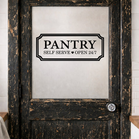 Wooden pantry door with a vinyl decal reading 'Pantry Self Serve Open 24/7' on a white tiled wall background.